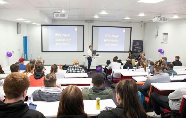 Animation course seminar in a modern classroom with engaging presenter and dual screens.