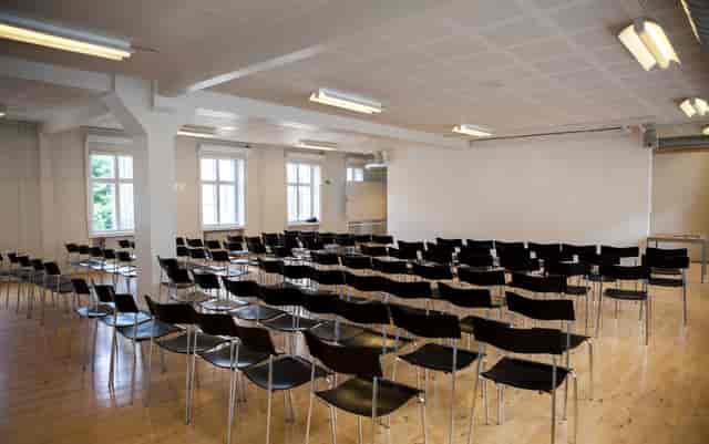 Lecture Room at Royal Danish Academy, spacious with black chairs for seminars and presentations.