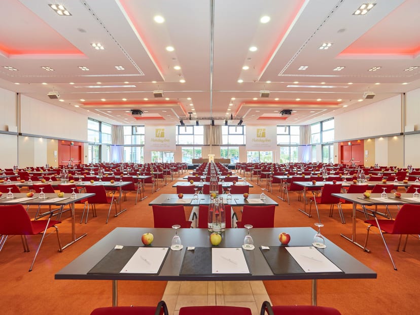 Meeting room at Holiday Inn Berlin with modern red chairs for conferences and events.