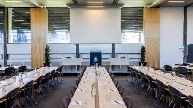 Modern meeting room with long table, ideal for conferences and networking events.