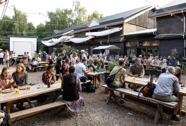 Vibrant outdoor networking event with communal tables and rustic charm in BaneGaarden.