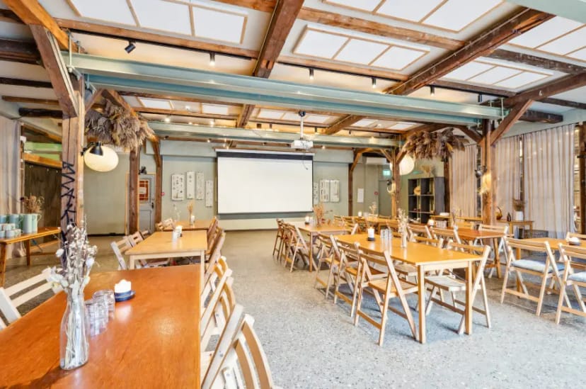 Spacious rustic event venue with wooden beams, ideal for workshops and gatherings.