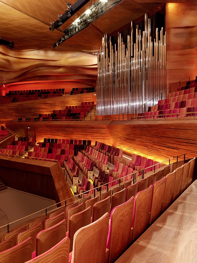 Sophisticated concert hall with tiered wooden seating for optimal acoustics and ambiance.