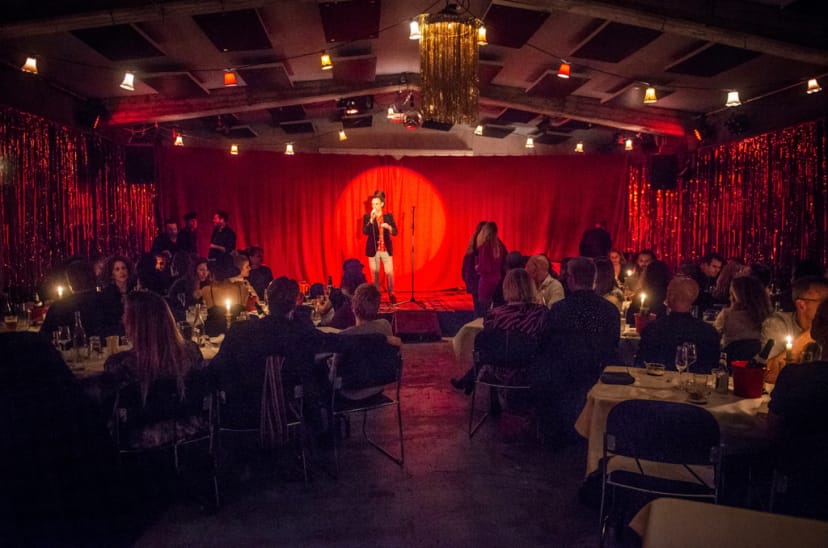 Vibrant H15 Kødbyen event space set for cabaret performance with dim lighting and red curtains.