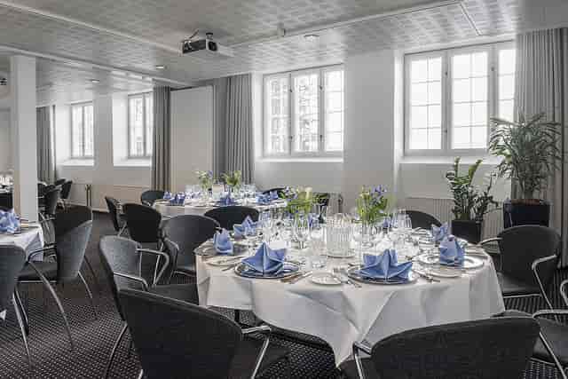 Event space with round tables and blue decor for corporate meetings at Hotel Koldingfjord.