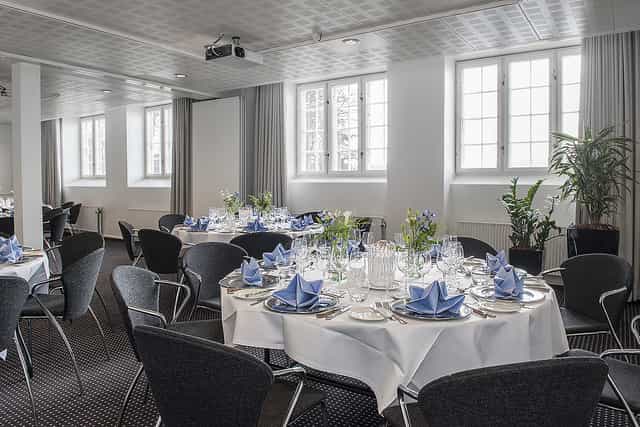 Event space with round tables and blue decor for corporate meetings at Hotel Koldingfjord.