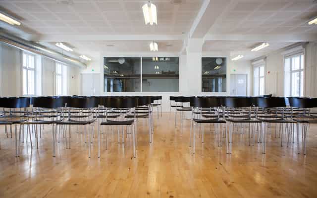 International school assembly hall with sleek black chairs, ideal for corporate meetings.