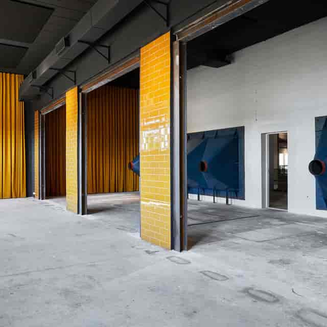 Versatile event space Maskinrummet with bold yellow and blue, ideal for workshops and exhibitions.