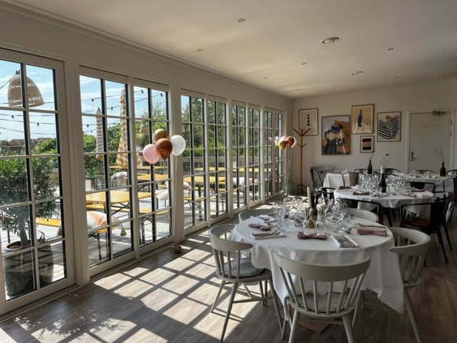 Private dining venue with elegant tables and natural light for events and celebrations.