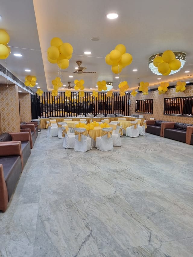 Banquet hall set for wedding or event with round tables and yellow decor.