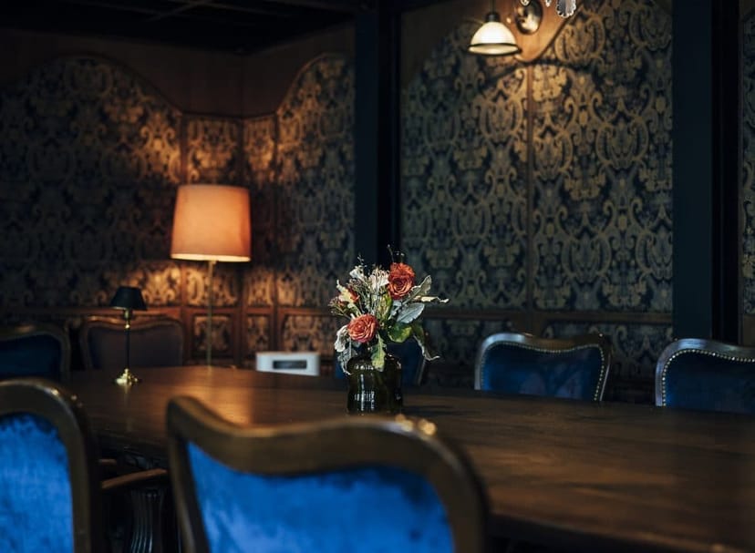 Sophisticated private event space with elegant wooden table and blue velvet chairs.