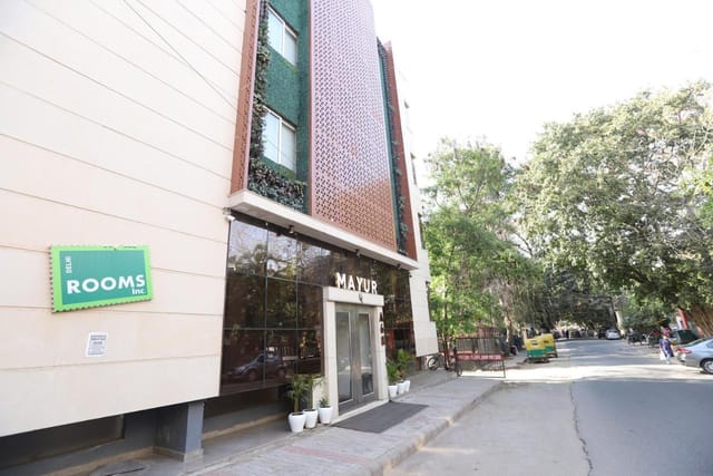 Modern Mayur Hotel entrance with lush greenery, perfect for events and meetings.