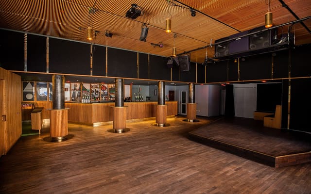 Spacious Ideal Bar venue with polished wood floor for corporate events and social parties.