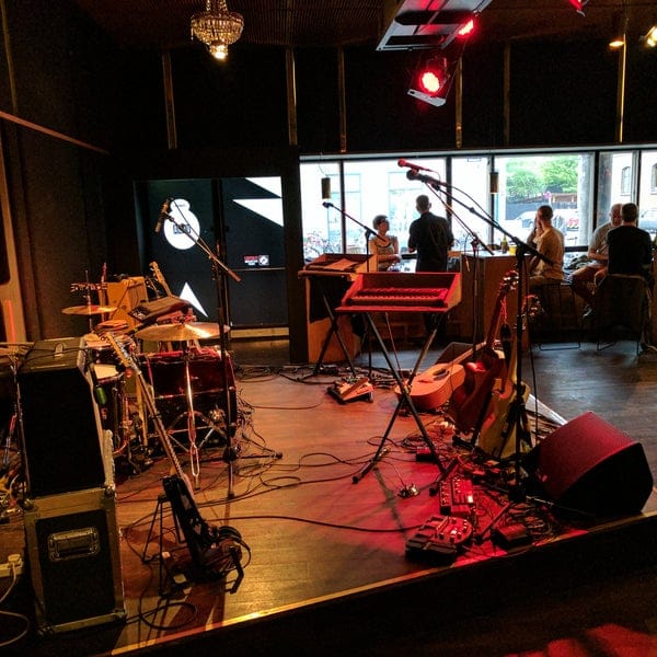 Ideal Bar in VEGA set for live music event with instruments and vibrant social atmosphere.