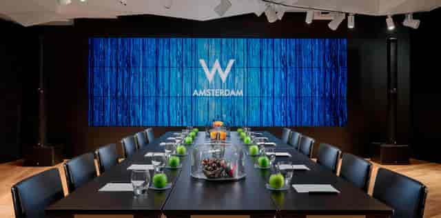 Modern meeting space in NIM Amsterdam with a large digital display for corporate events.