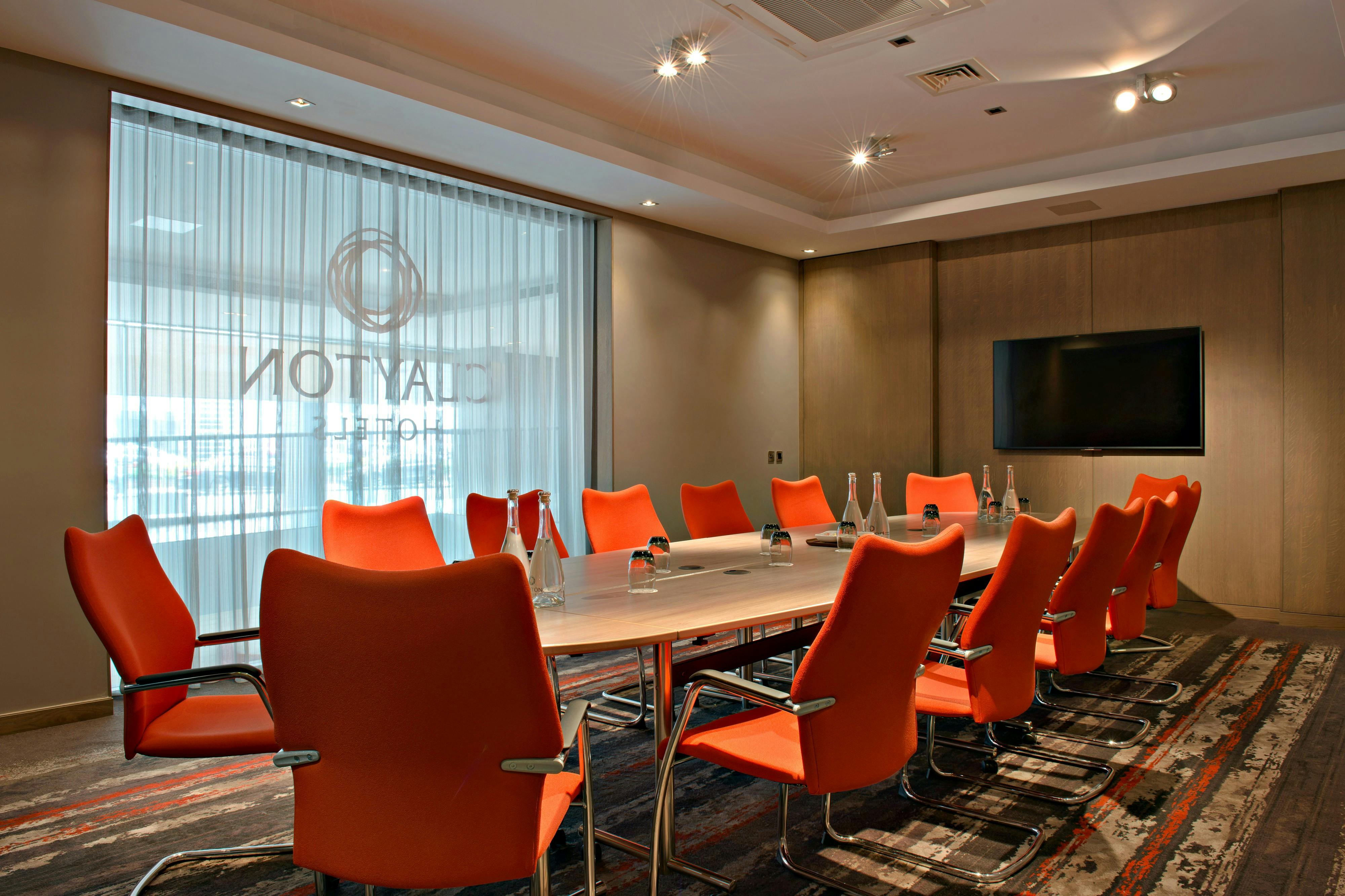 Modern conference room at Clayton Hotel Chiswick with ergonomic orange chairs for corporate events.