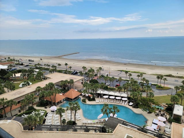 Coastal wedding venue at The San Luis Resort with pool and palm trees, perfect for events.