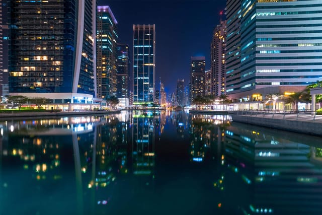Hatta skyline at night, reflecting lights on waterway; ideal for events and conferences.