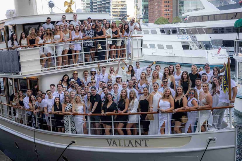 Attendees in themed attire enjoy a networking event on a Charles River boat.