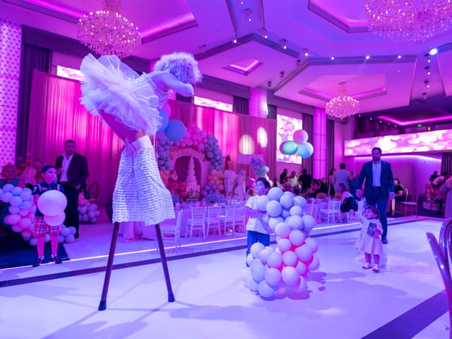 Sweet 16 Quinceañera party with stilt performer and purple lighting decor.