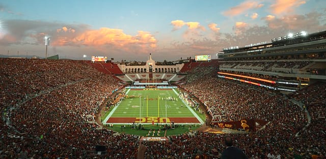 Los Angeles Coliseum filled with fans at sunset during a major sporting event.