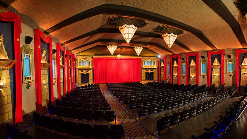 Vista Theatre auditorium with red drapes and chandeliers, ideal for events and presentations.