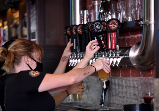 Bartender pouring drinks at The Brews Hall patio, perfect for casual celebrations.
