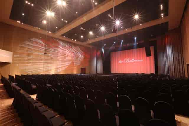 Ballroom auditorium with tiered seating and large stage for corporate events.
