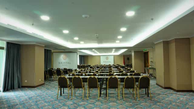 Sapphire Room at Kristal Hotel: spacious conference setup with projector and chairs.