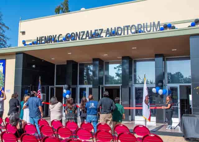 Henry C. Gonzalez Auditorium ribbon-cutting ceremony with vibrant crowd and festive decor.