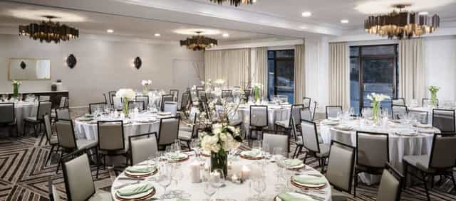 Elegant banquet venue at The Darcy with round tables and stylish chandeliers. Ideal for events.