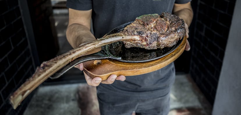 Tomahawk steak on wooden platter at upscale kitchen event, perfect for gatherings.