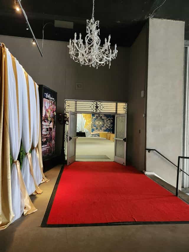 Elegant entrance to Curtain Call, featuring red carpet and stylish drapery for events.