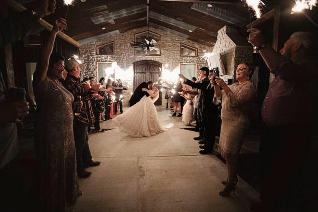 Bride and groom send-off with sparklers in rustic ballroom venue decor.