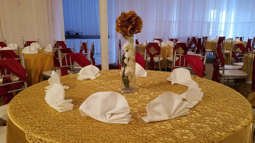 Elegant banquet hall table with golden cloth and floral centerpiece for formal events.
