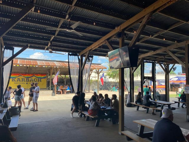Beer garden at Karbach Brewing Co. with shaded seating, ideal for gatherings and networking.