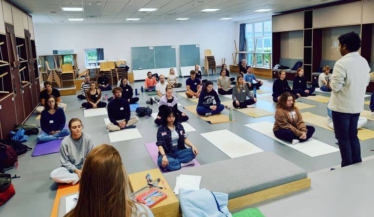 Meditation session in spacious Copenhagen Business School event room for wellness retreats.