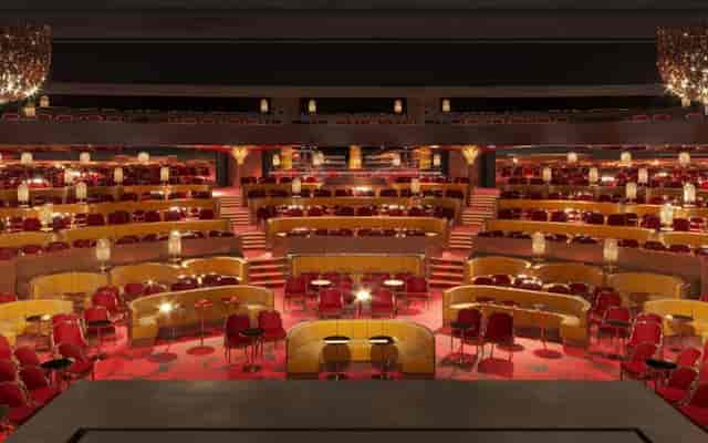 Auditorium with tiered seating and red chairs at Théâtre du Lido for events and conferences.
