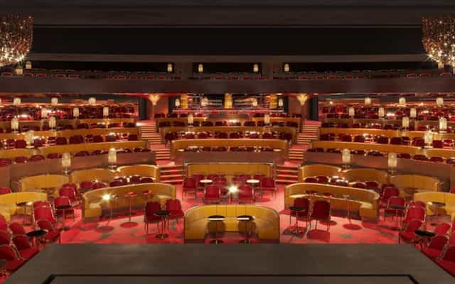Auditorium with tiered seating and red chairs at Théâtre du Lido for events and conferences.