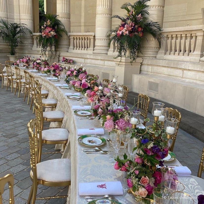 Elegant outdoor dining setup with pink floral arrangement at Palais Galliera event.