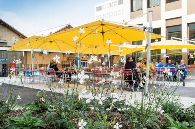 Outdoor restaurant event space with yellow umbrellas, ideal for networking and casual gatherings.