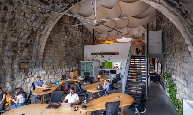 Cozy coworking space in Impact Hub Zürich with arched stone ceiling, ideal for meetings.