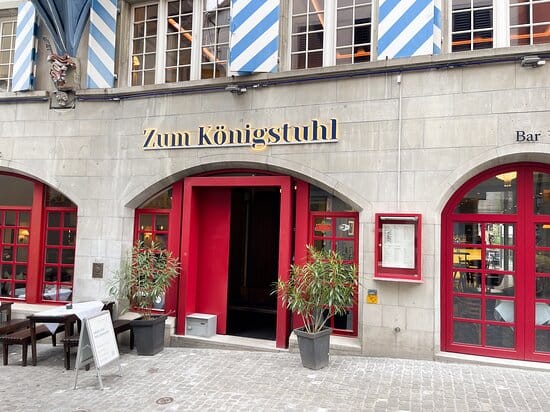 Charming entrance of Zum Königstuhl restaurant with red doors, ideal for events and meetings.