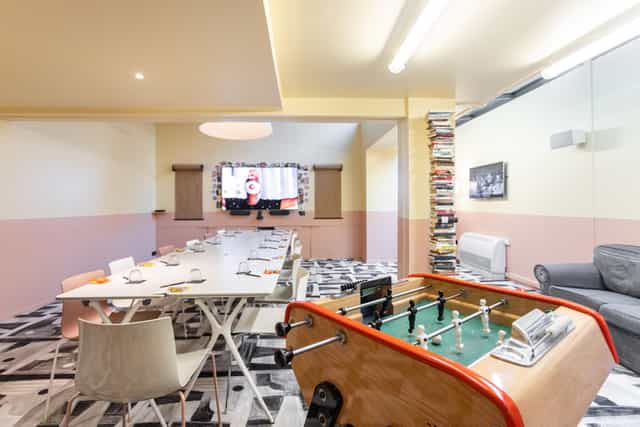Modern meeting room with long table and foosball for creative team-building events.