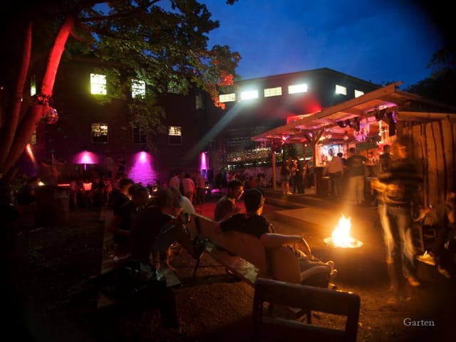 Nightclub outdoor event with ambient lighting, seating, and a cozy fire pit for socializing.