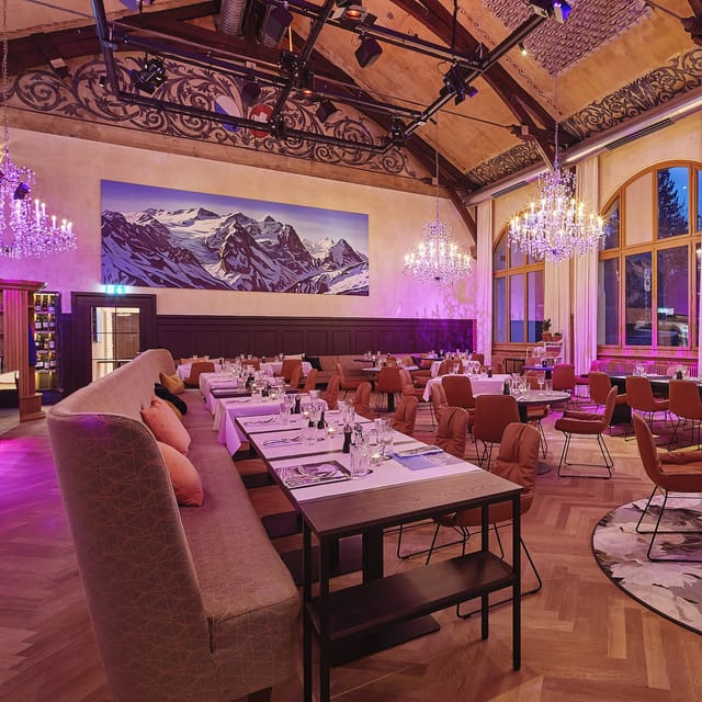 Elegant event space at Gasthaus Albisgütli with chandelier and mountain mural for gatherings.
