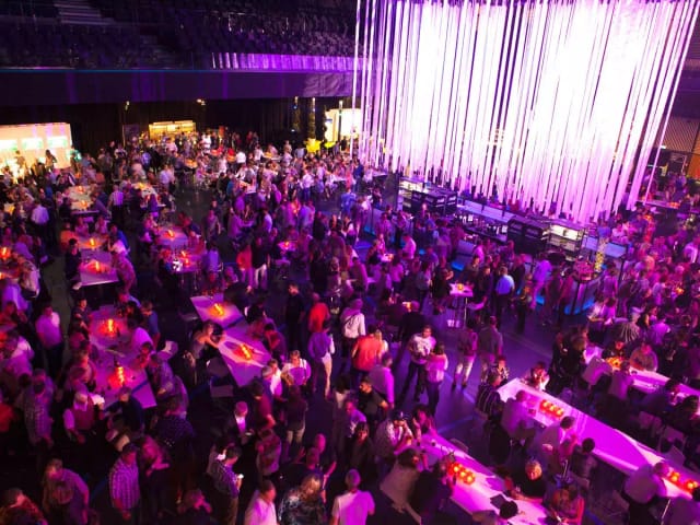 Vibrant event at THE HALL with dramatic lighting and bustling guests networking.