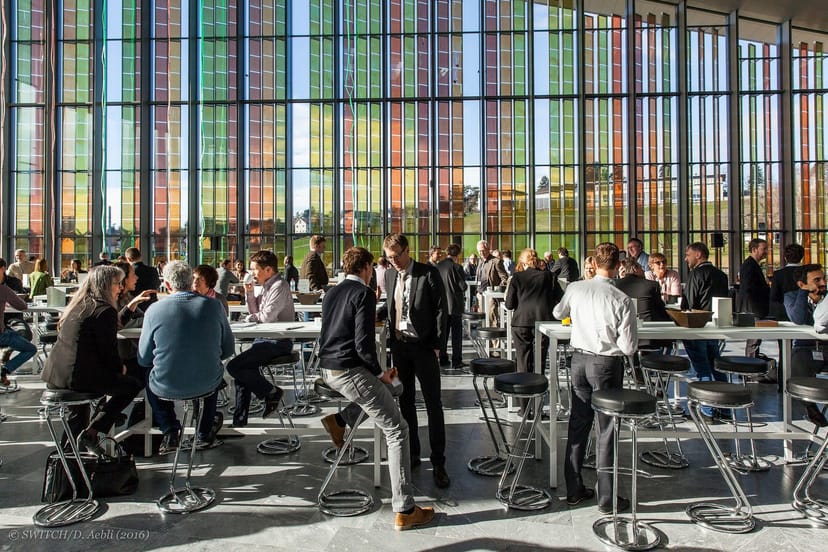 Networking event in Plenary Garden, SwissTech Center with colorful glass panels.