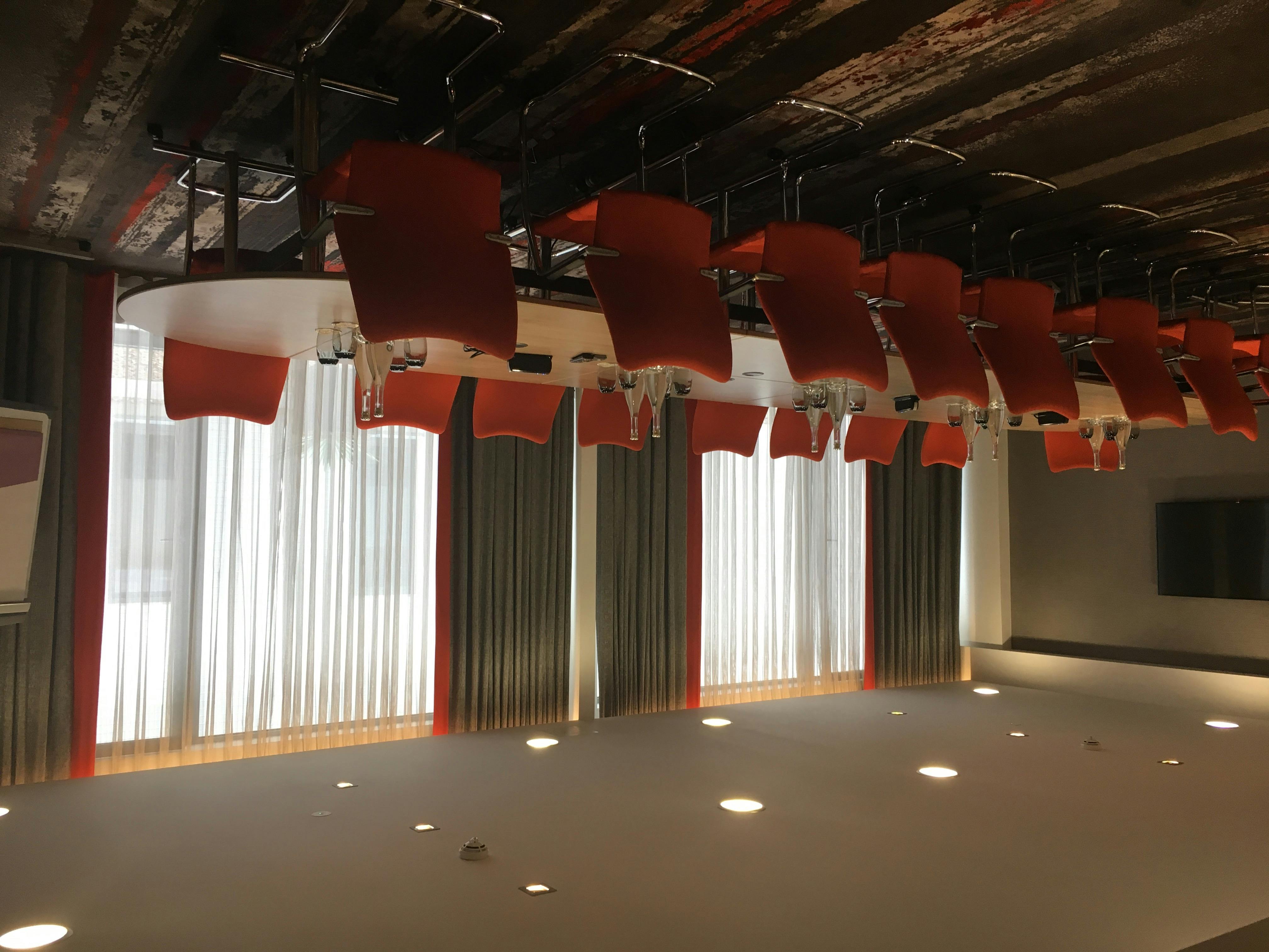 Modern Gunnersbury Suite meeting room with orange chairs and natural light, ideal for events.