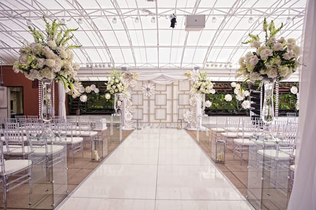 Elegant wedding ceremony in Banquet Hall, featuring floral arrangements and modern acrylic chairs.